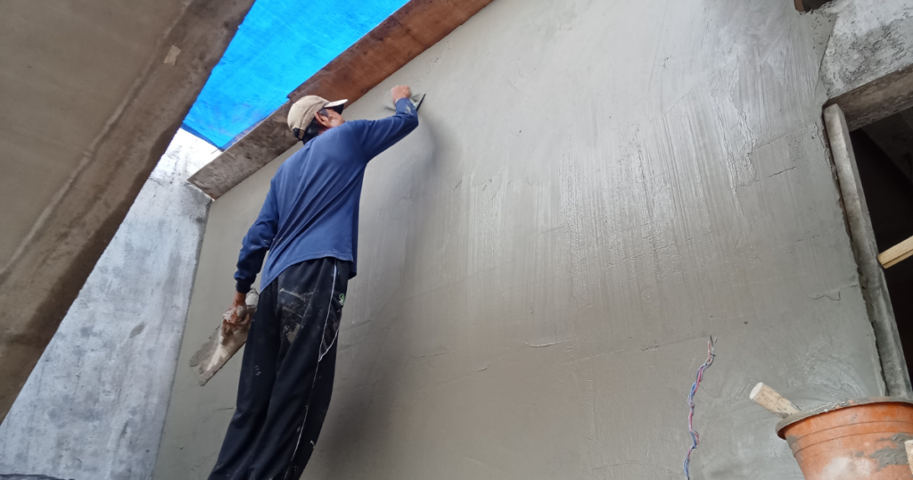trabalhador aplicando argamassa de reboco em parede